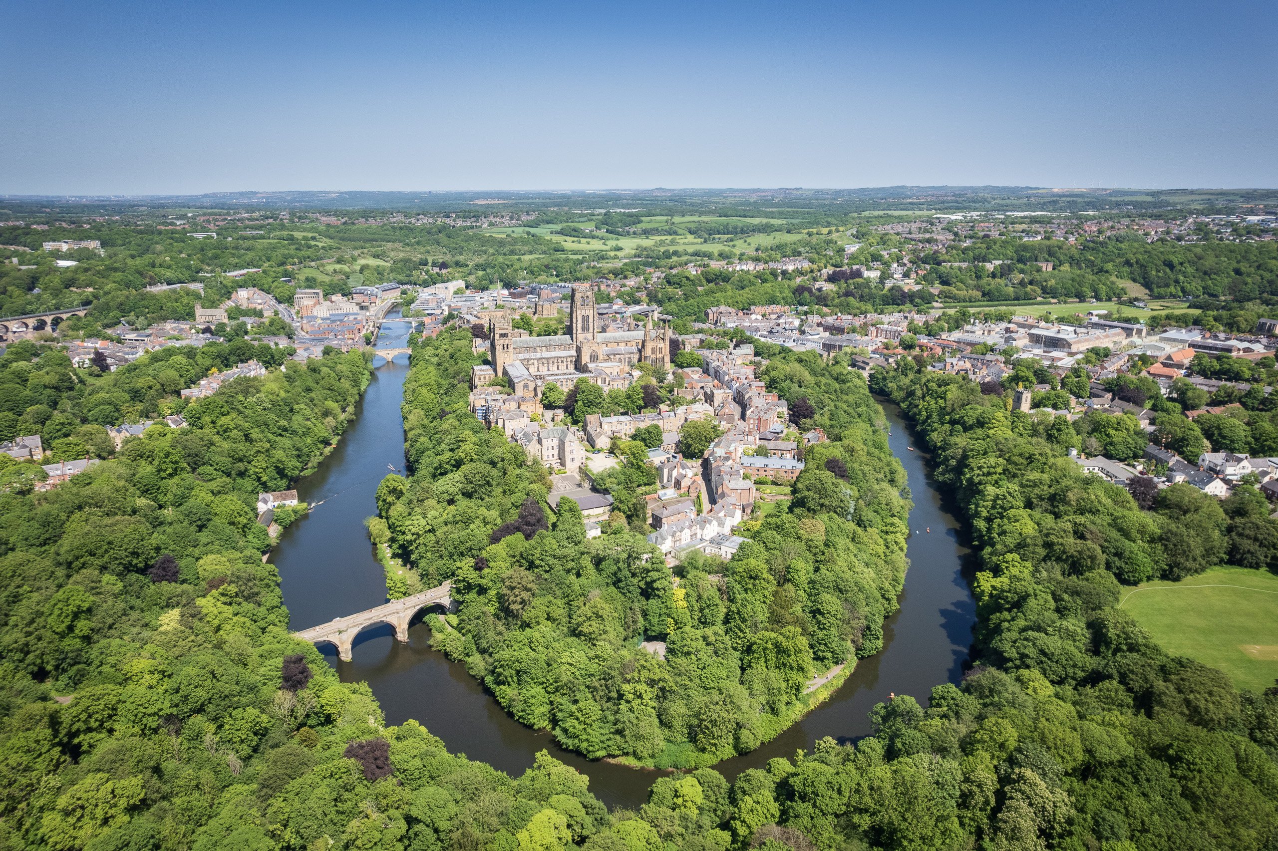Aerial view of Durham Cathedral and the city centre encircled by a bend in the River Wear, surrounded by dense woodland.