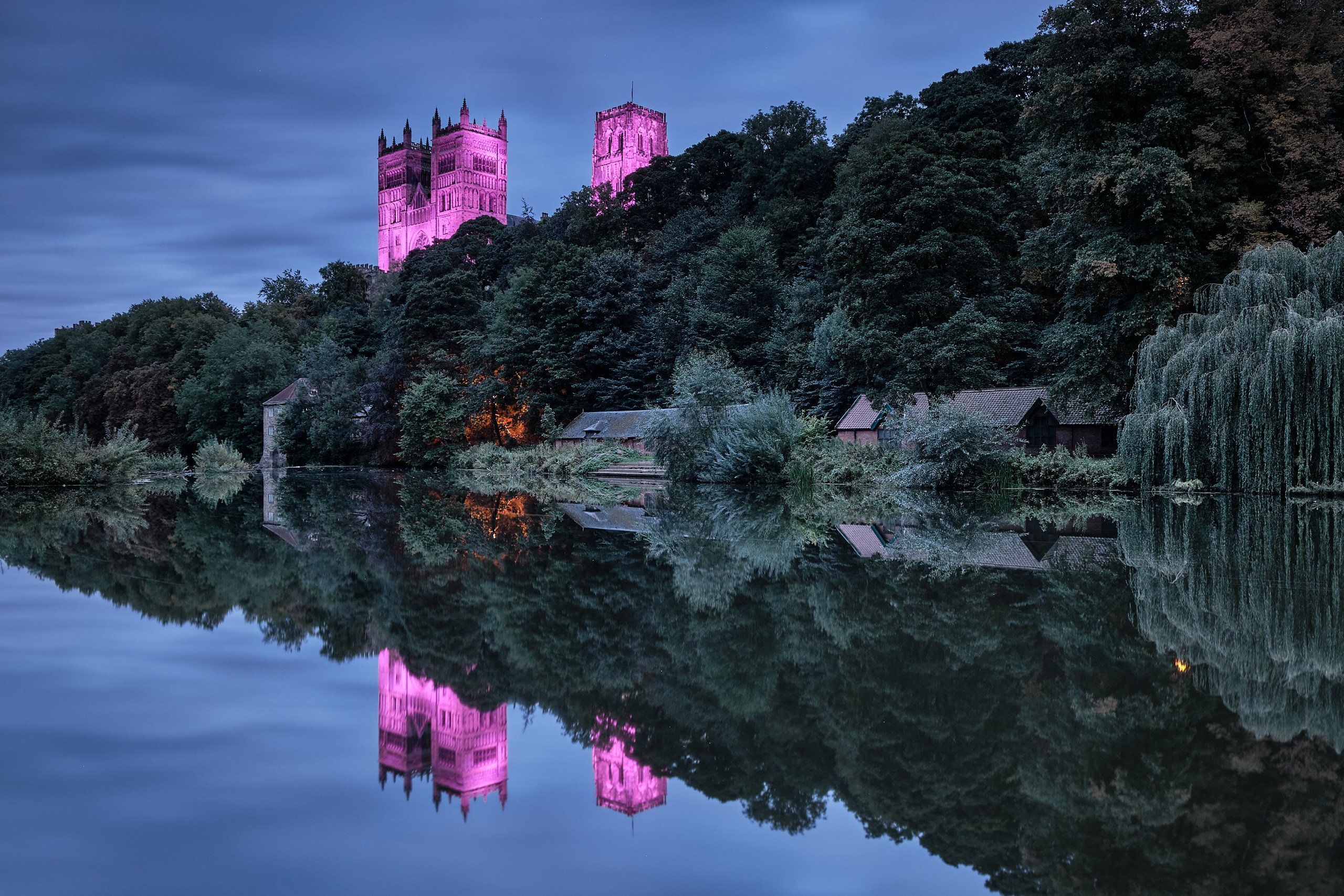 Durham Cathedral towers lit pink, reflected in the still River Wear