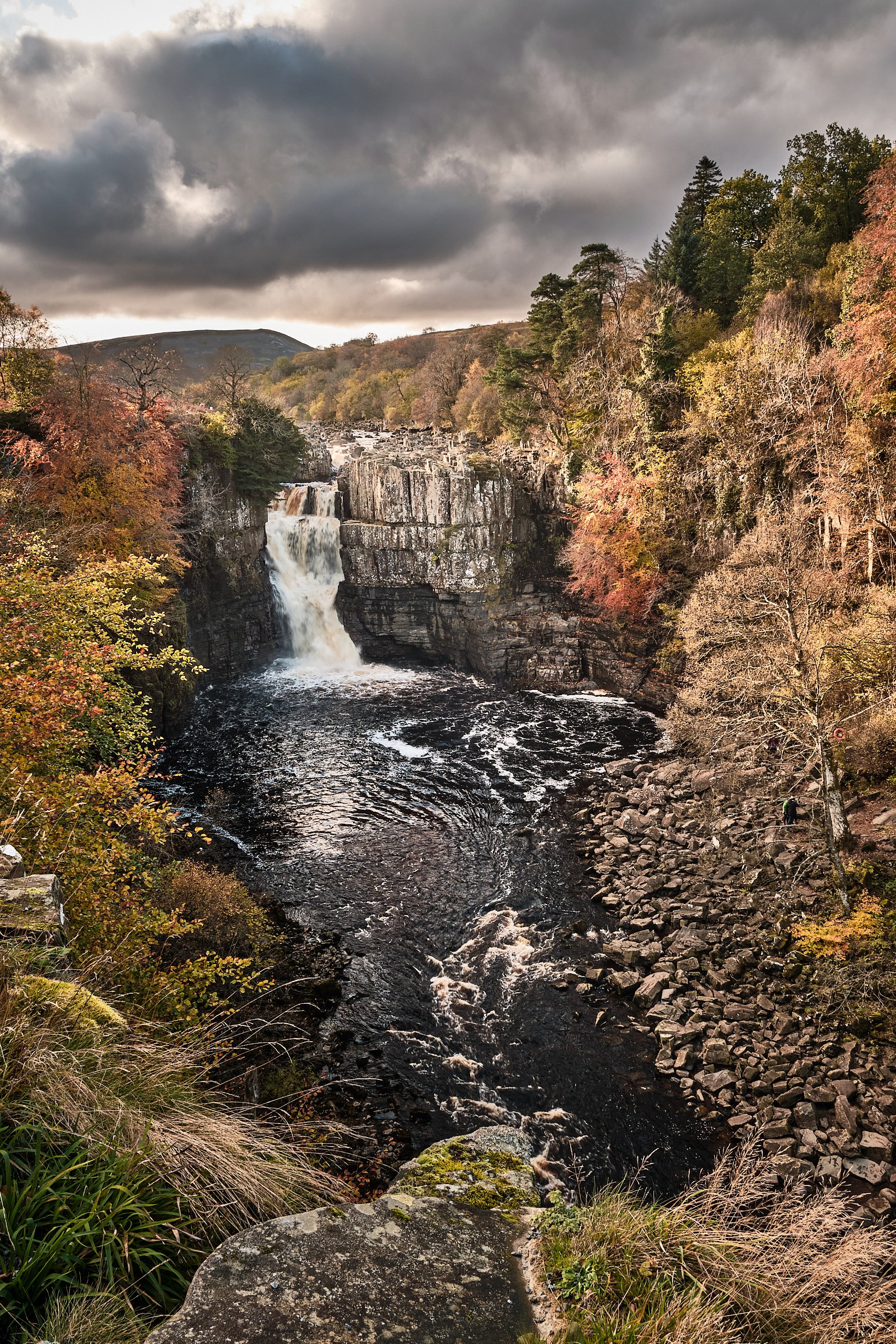 Teesdale waterfall crashing over dolerite cliffs under stormy autumn sky
