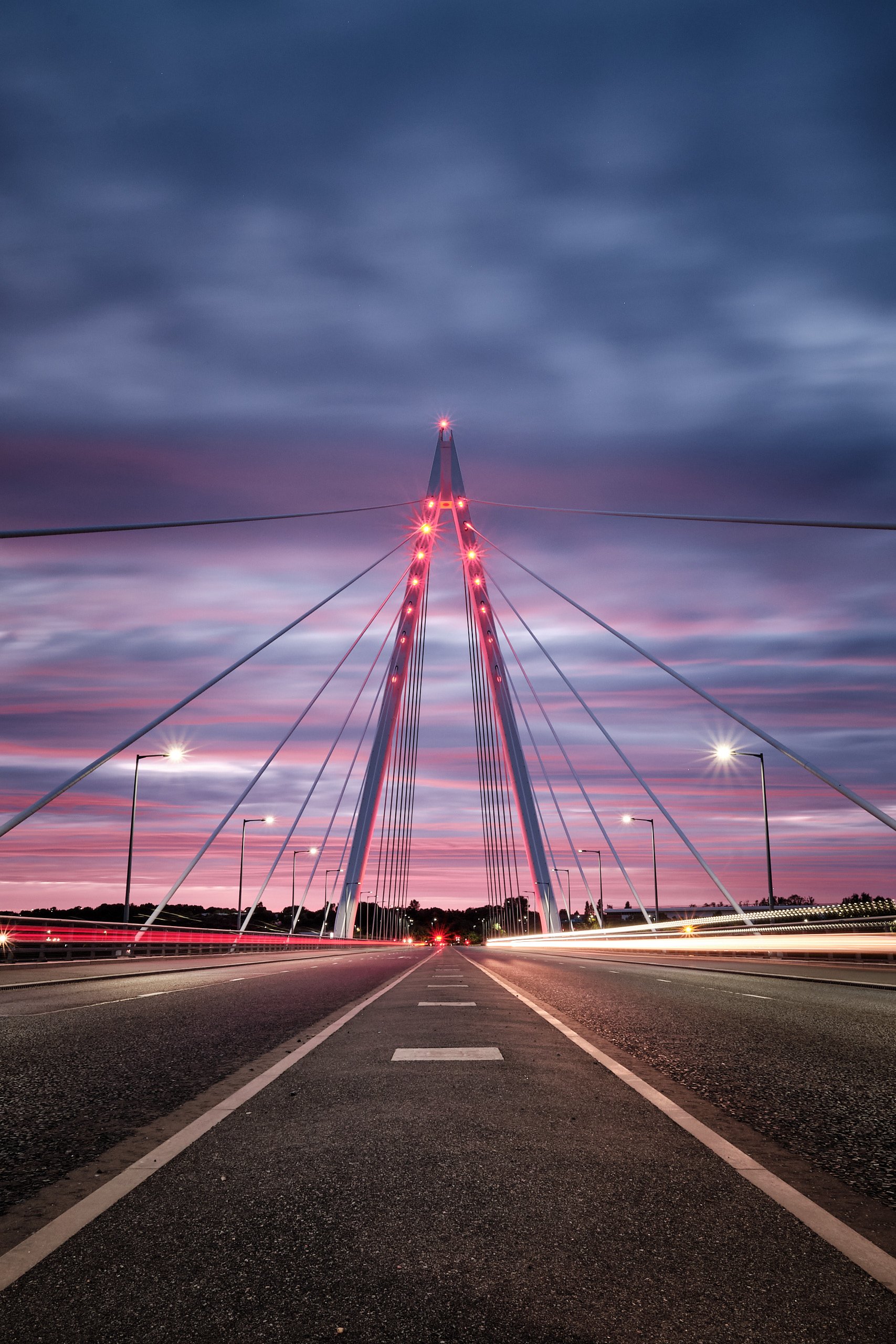 Northern Spire Bridge pylon lit red against a pink dusk sky