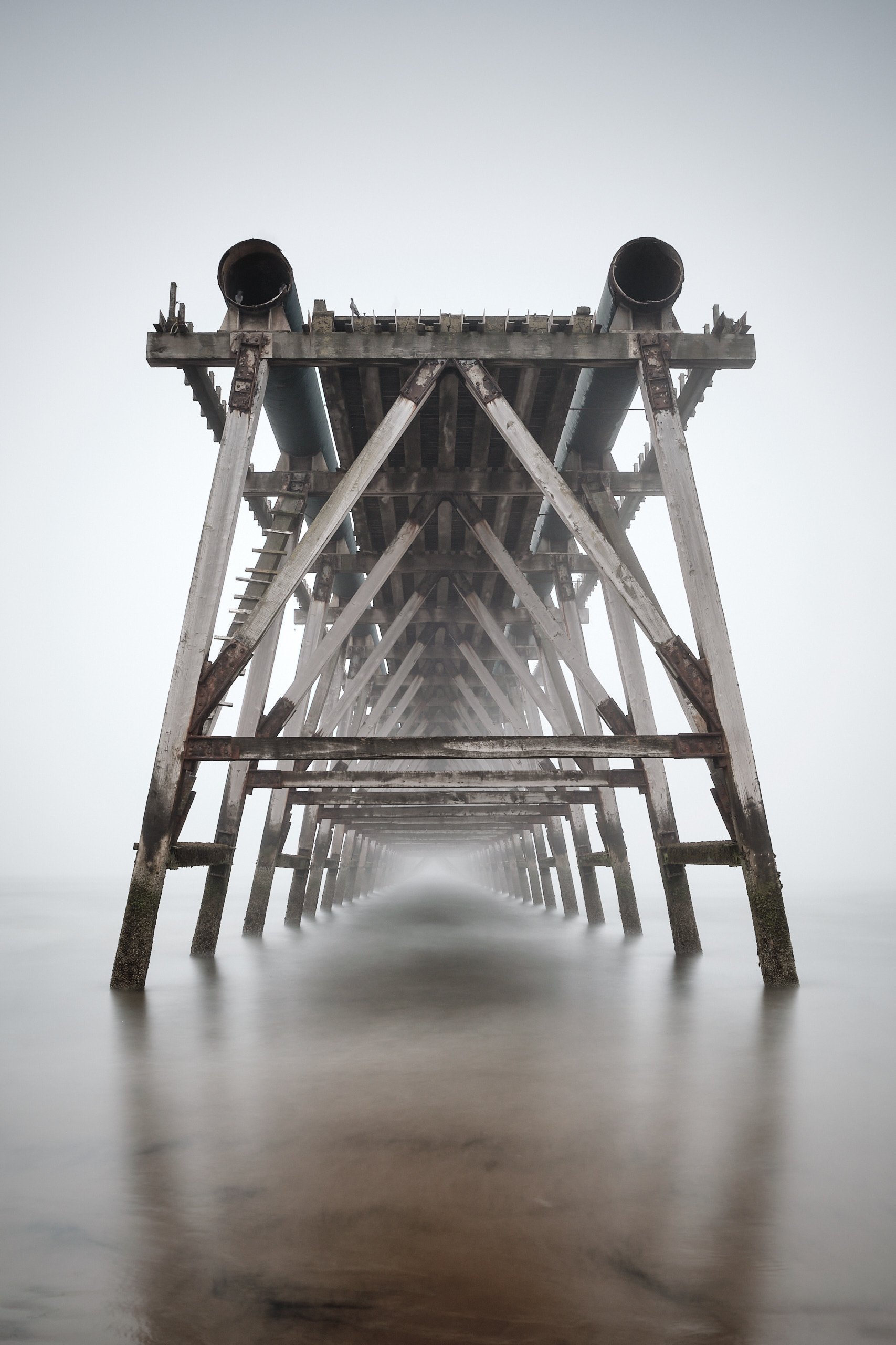 Symmetrical underside of Steetley Pier structure over misty sea